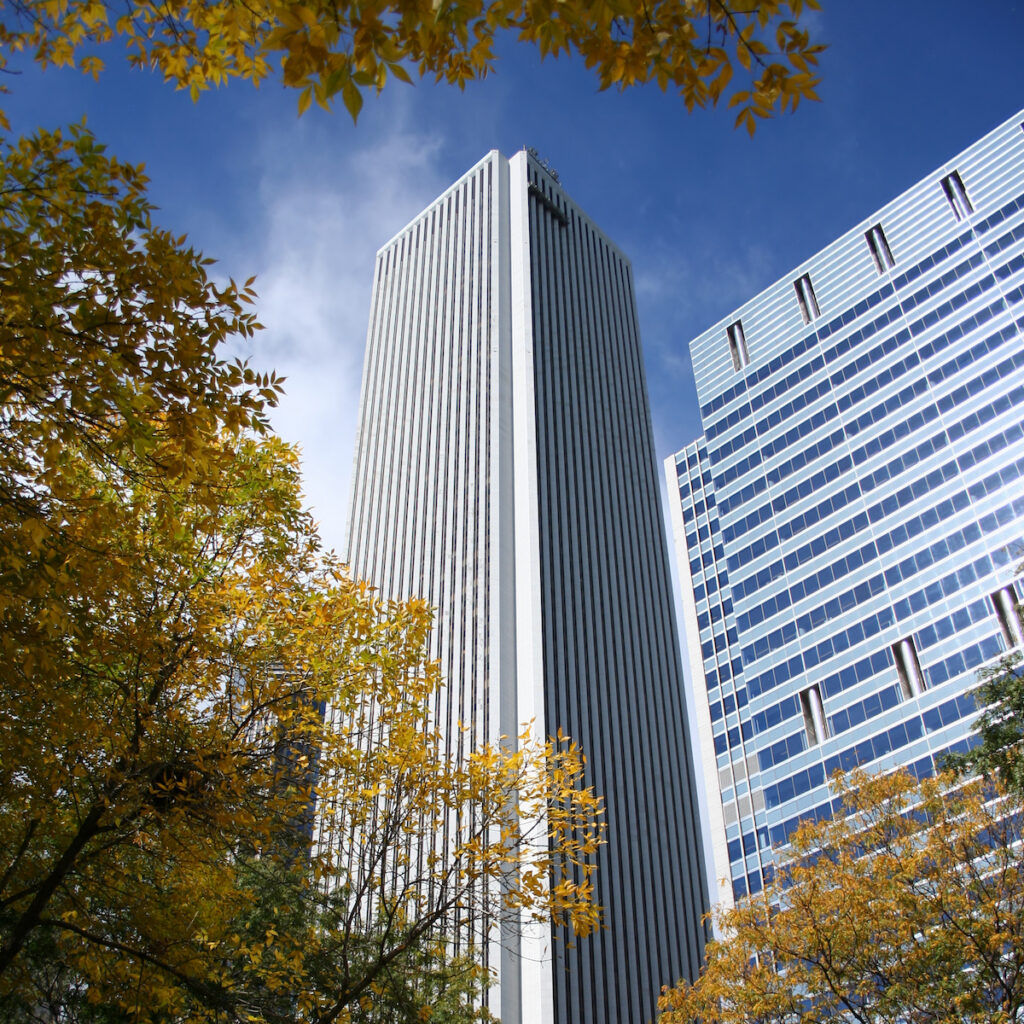 Street Level View of Aon Building with fall foliage on trees in foreground and white mount airy granite facade